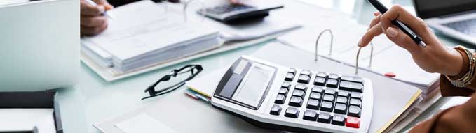 Close-up Of Two Businesspeople Calculating Financial Statement At Desk