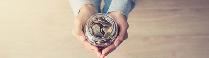 Young woman hands holding glass jar with money (coins) inside - panoramic banner background, top view, with copy space