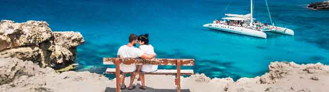 A couple sits on a bench and looks at the lagoon. Honeymoon lovers. Man and woman on the island. Couple in love on vacation. A voucher for a cruise trip. Sea tour. Honeymoon trip. Wedding travel