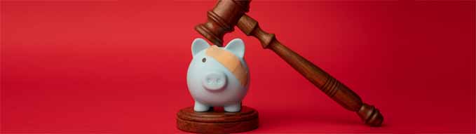 Broken pink piggy bank with beige adhesive with wooden judge gavel on a red background. Law and bankruptcy concept