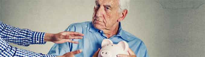 Closeup portrait senior man grandfather holding piggy bank looking suspicious trying to protect his savings from being stolen isolated on gray wall background. Financial fraud concept