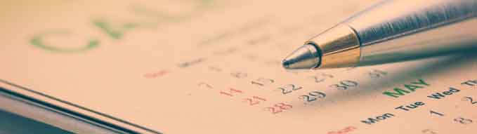 Calendar planner stationery concept : Blue metal pen on a paper desk calendar. A calendar is a system of organizing days for commercial or administrative purposes by giving names to a period of time.