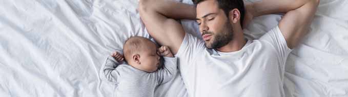 top view of handsome father sleeping on bed with little baby boy
