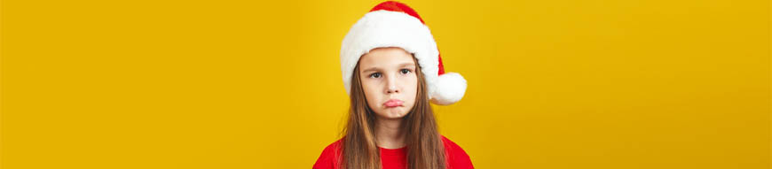 Upset little girl wearing Christmas costume standing isolated over yellow background wall in studio