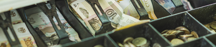 Currency in rubles fills a cash register drawer with organized notes and coins during a transaction at a retail checkout The setting reflects a typical shopping environment.