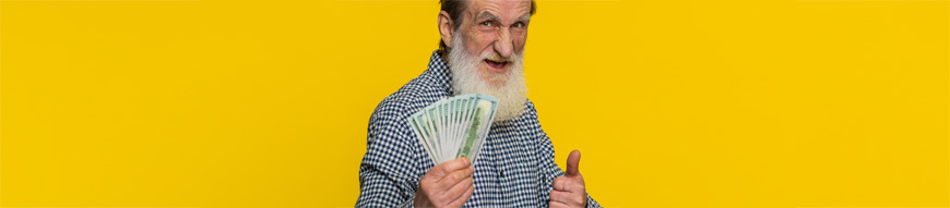 Rich happy senior old man waving money dollar cash banknotes bills like a fan, success business career, lottery winner, big income wealth pension. Elderly grandfather pensioner on yellow background